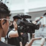 man in black framed eyeglasses holding black video camera