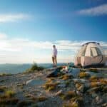 man in white t-shirt standing near white dome tent during daytime