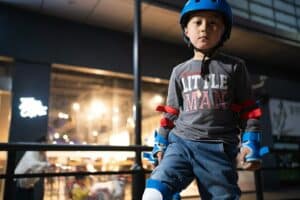 boy in black and red zip up jacket and blue denim jeans wearing blue helmet