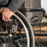 Gros plan de la main d'une personne sur la roue d'un fauteuil roulant, paysage désertique en arrière-plan