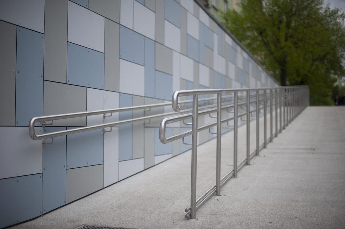 Rampe d'accès en métal le long d'une façade moderne en carrelage gris clair