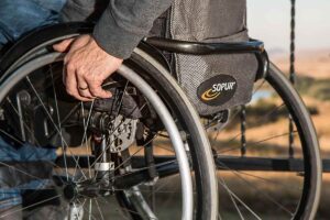 Gros plan de la main d'une personne sur la roue d'un fauteuil roulant, paysage désertique en arrière-plan