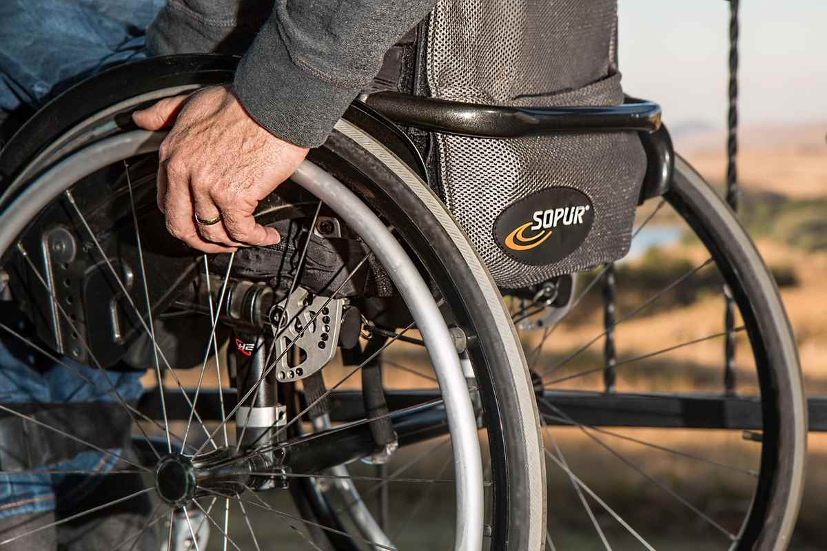 Gros plan de la main d'une personne sur la roue d'un fauteuil roulant, paysage désertique en arrière-plan