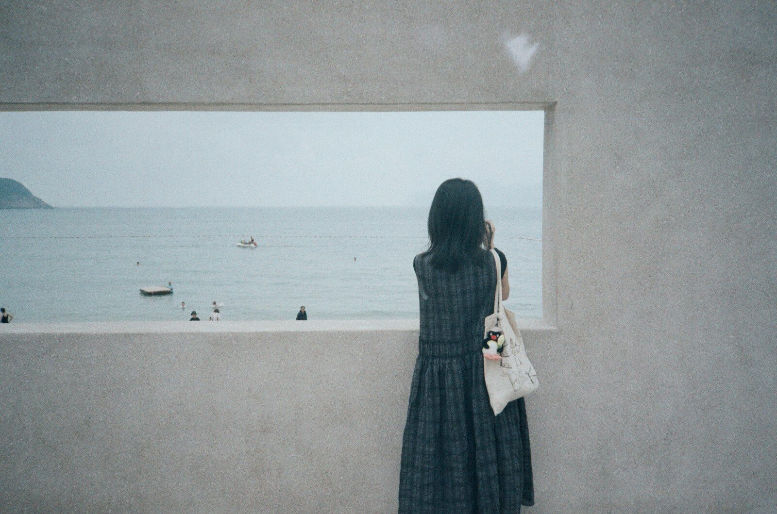 Woman in long dress looking out window at ocean