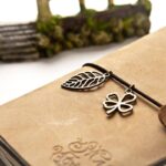 Livre en cuir avec bretelle et deux breloques métalliques