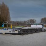 Bateau sur un canal avec un ciel gris et des arbres