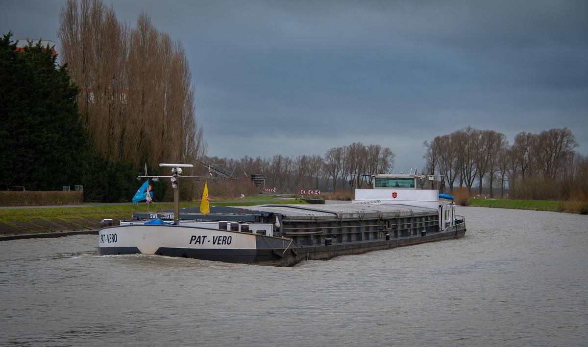 Bateau sur un canal avec un ciel gris et des arbres