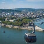 A cable car going over a river with a city in the background
