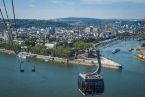 A cable car going over a river with a city in the background
